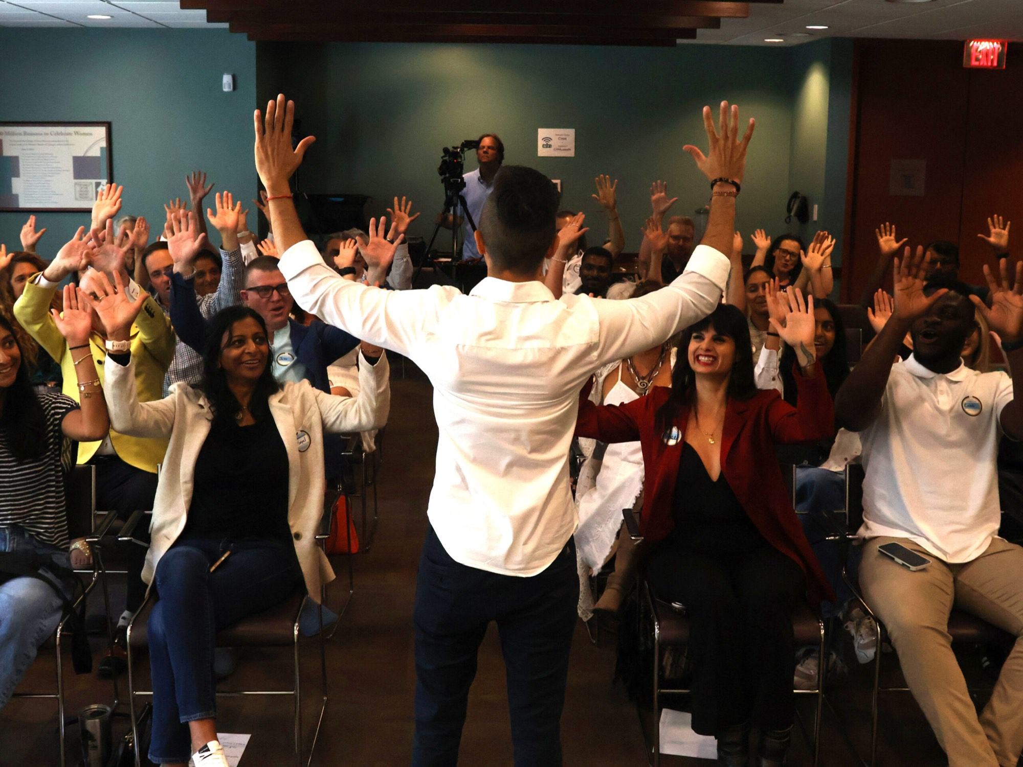 Cal Amir facing a full room with every hand raised